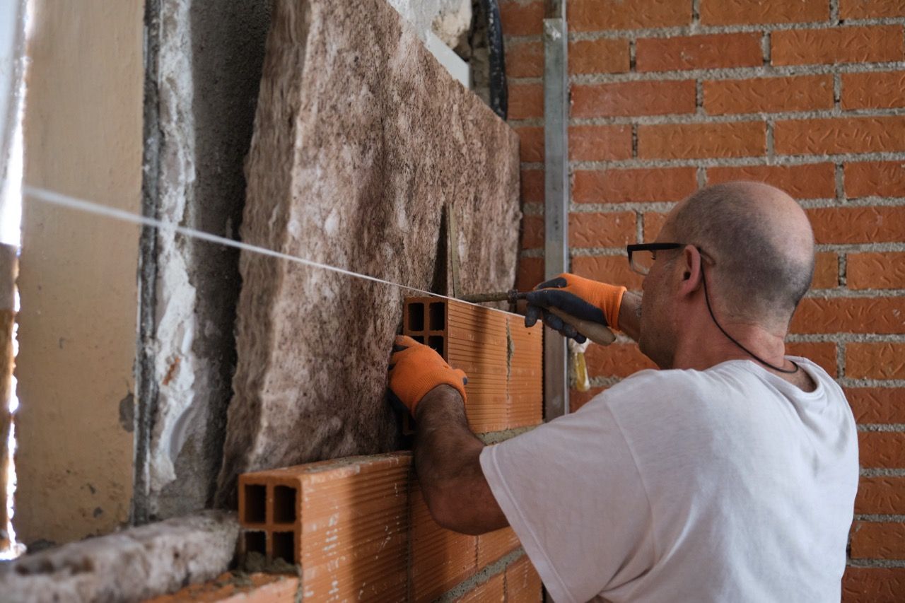 Builder laying bricks after placing an acoustic and thermal insulation. Impermeabilización